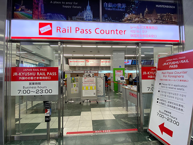 博多駅のみどりの窓口でJR九州レールパスを購入する旅行者。