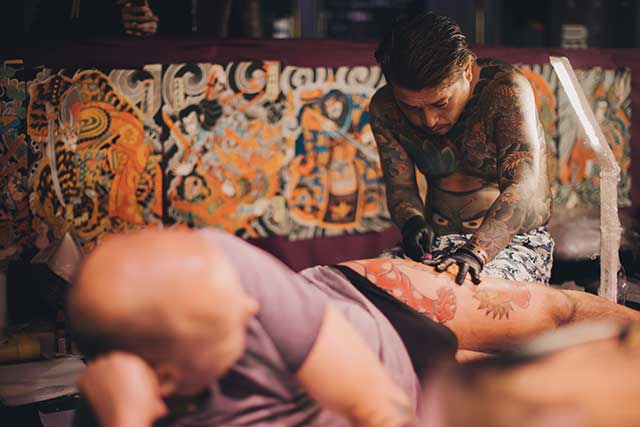 A Japanese irezumi tattoo artist works on a client at an overseas event
Mykola Romanovskyy/Shutterstock.com