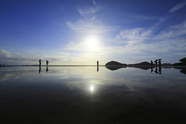 Blue sky is beautifully reflected in the tide pools that form in the sand, creating a natural mirror effect