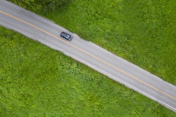 Birds eye view, a car driving through the wide expanse of the Aso-Kuju National Park