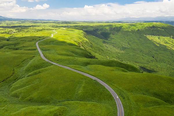 A winding coutry road slices through the grassy plains of Aso-Kuju National Park