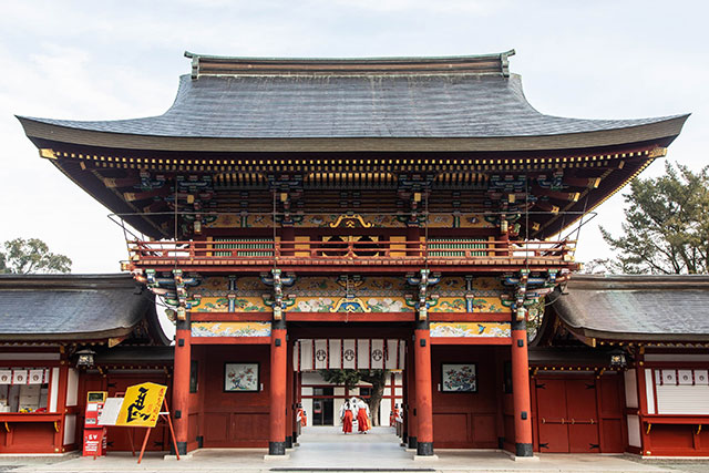 Shrine staff go about their morning duties, as seen from behind the main gate